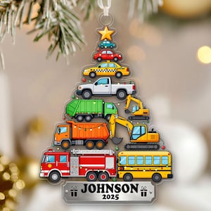 May include: Clear acrylic Christmas ornament shaped like a tree, featuring colorful illustrations of various vehicles. The ornament includes a star, cars, a taxi, a pickup truck, a garbage truck, an excavator, a dump truck, a fire truck, and a school bus. The name "JOHNSON" and the year "2025" are printed on the bottom.