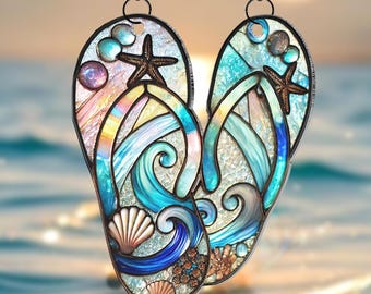 May include: A stained glass suncatcher shaped like a pair of flip flops with a beach scene. The flip flops are blue, green, and white with seashells, starfish, and waves.