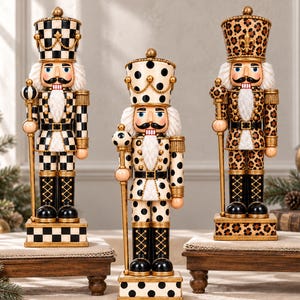 May include: Three decorative nutcracker figures standing on individual wooden platforms. The left figure features a black and white checkerboard pattern, the center has black polka dots, and the right displays a brown leopard print pattern.