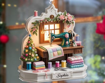 May include: A Christmas ornament featuring a miniature sewing room scene. It includes a teal sewing machine, a small Christmas tree, spools of thread, and a quilt. The ornament is decorated with flowers and a red and white checkered bow.
