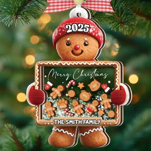 May include: A gingerbread man Christmas ornament with a red hat and mittens. The ornament has a chalkboard sign that reads "Merry Christmas" and "The Smith Family." The year "2025" is printed on the hat. The ornament is hanging from a Christmas tree.