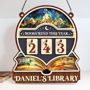 May include: Wooden sign with the text "BOOKS READ THIS YEAR" and the number "243". The sign features a mountain and starry sky design at the top and an open book at the bottom. The text "DANIEL'S LIBRARY" is at the bottom.
