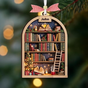 May include: Wooden Christmas ornament shaped as a bookshelf, with the name "John" at the top. The ornament features a miniature Christmas tree, books, a ladder, and a red and white checked bow.