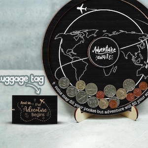 May include: A black wooden world map coin bank with the text "Adventure awaits:" and a plane flying over the map. The coin bank has a stand and the text "9 coins may fill your pocket but adventure will fill your soul" is written around the edge of the map. A small tag with the text "And so... the Adventure Begins" is in the foreground.