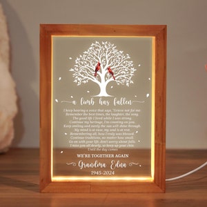 May include: A wooden framed illuminated sign with a white tree silhouette and two red cardinals. The sign has a poem about loss and remembrance, and the text "Grandma Edna 1945-2024".