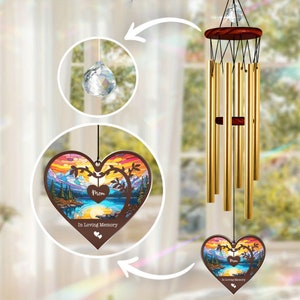 Könnte beinhalten: Ein herzförmiger Windspiel mit einem Buntglasdesign eines Sees und Bergen. Das Windspiel hat einen Kristall-Prisma und die Worte "Mom In Loving Memory" auf dem Herzen.