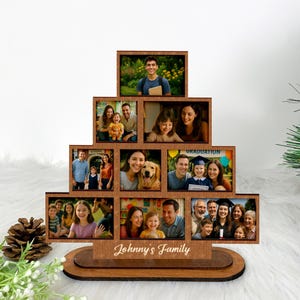 Peut inclure: Un présentoir photo familial en bois avec plusieurs cadres rectangulaires disposés en gradins. Les cadres contiennent diverses photos de famille. La base du présentoir porte l'inscription "Johnny's Family".