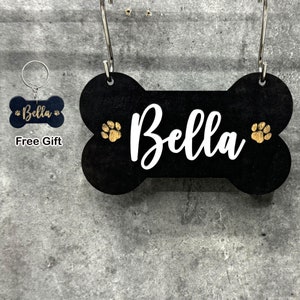 May include: Black wooden bone-shaped dog tag with the name "Bella" in white lettering and gold paw prints. A smaller black bone-shaped tag with the name "Bella" is included as a free gift.