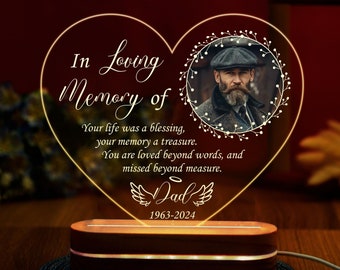 May include: A heart-shaped acrylic memorial light with a photo of a man in a cap and a quote that reads "In Loving Memory of Your life was a blessing, your memory a treasure. You are loved beyond words, and missed beyond measure. Dad 1963-2024".