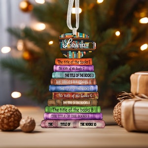 May include: A personalized Christmas ornament featuring a coffee cup with a stack of books. The cup has the name "Laura" written on it. The books have titles like "The title of the books 1" and "The title of the books 10".
