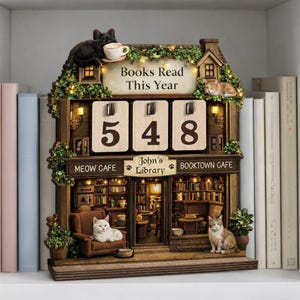May include: A decorative wooden cat-themed calendar with the text "Books Read This Year" and the numbers "548". The calendar features a miniature library scene with cats, lights, and the names "Meow Cafe", "John's Library", and "Booktown Cafe".