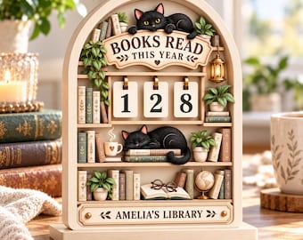 May include: A wooden arched bookshelf display featuring two black cats, potted plants, and a flip-style counter showing the number 128. The sign reads BOOKS READ THIS YEAR and AMELIA'S LIBRARY. Includes miniature books, a lantern, and glasses.