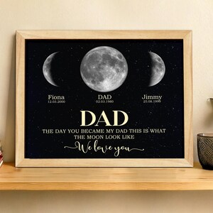 May include: A framed print with a black background featuring three moon phases and the word "DAD" in large, gold lettering. The text reads "THE DAY YOU BECAME MY DAD THIS IS WHAT THE MOON LOOK LIKE" and "We love you."