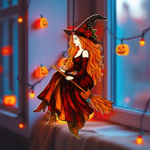 May include: A stained glass witch decoration with long orange hair, a black hat, and a red dress, riding a broom. The witch is suspended by a chain. The background includes a window, string lights, and jack-o'-lanterns.