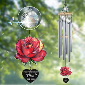 Könnte beinhalten: Ein Gedenk-Windspiel mit einem roten Rosenmuster und einem Kristallprisma. Das Windspiel hat einen herzförmigen Anhänger mit dem Text "IN LOVING MEMORY OF Mom 1982-2025". Die Klangspiele sind silberfarben und hängen an einer Holzspitze.