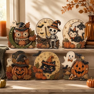 Pode incluir: Um conjunto de seis figuras decorativas de Halloween com uma coruja, um esqueleto, um gato, uma abóbora e um fantasma. Cada peça incorpora elementos sazonais como luas crescentes, luas cheias, morcegos, folhas de outono e abóboras.