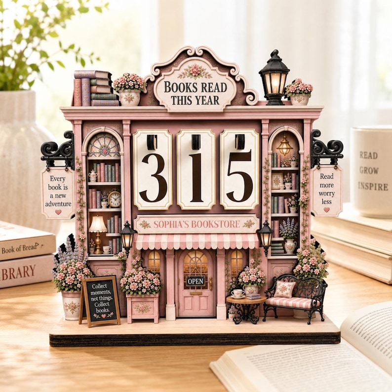 May include: A pink wooden bookstore-themed perpetual calendar featuring the text BOOKS READ THIS YEAR, SOPHIA'S BOOKSTORE, and signs reading Every book is a new adventure, Read more worry less, and Collect moments, not things. Collect books.