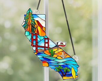 May include: A stained glass window hanging with a depiction of the state of California. The outline of the state is filled with colorful images of the Golden Gate Bridge, palm trees, a surfboard, and a desert landscape.