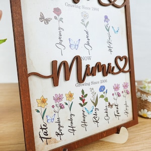 May include: A wooden framed sign with a heart-shaped cutout and the word "Mimi" in brown lettering. The sign features a floral design with names and dates, including "Growing Since 1984" and "Growing Since 2006".