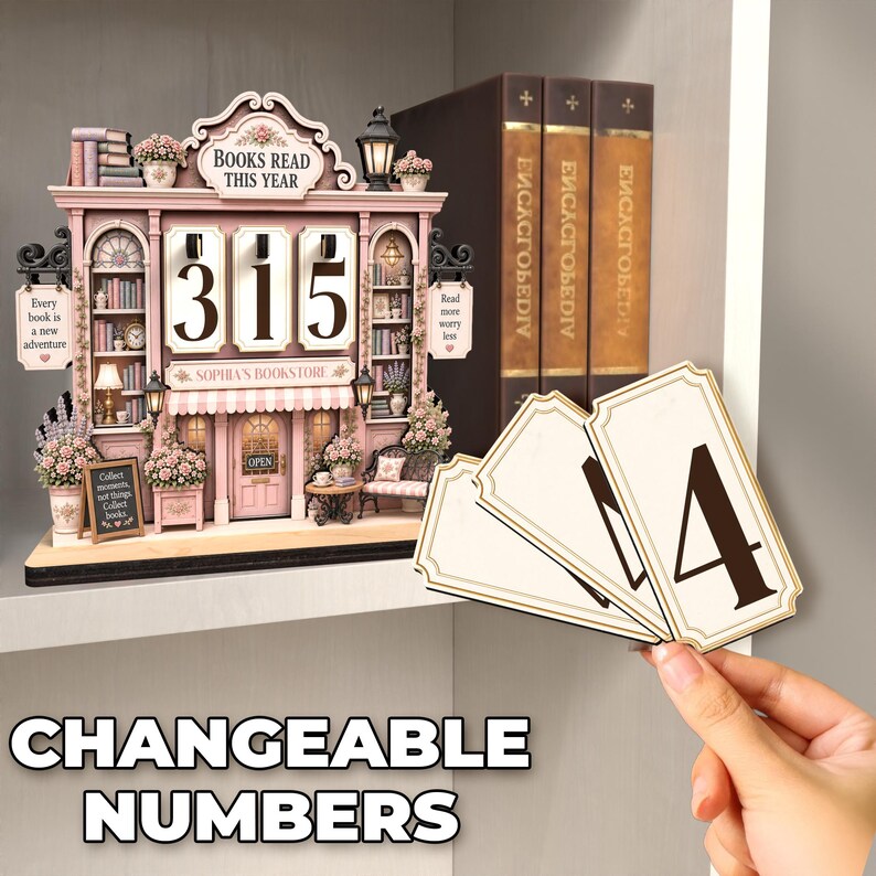 May include: A miniature bookstore display with pink accents, featuring the text "BOOKS READ THIS YEAR" and "SOPHIA'S BOOKSTORE". It includes shelves of books, floral decorations, and three slots for changeable numbers, with additional number cards provided.