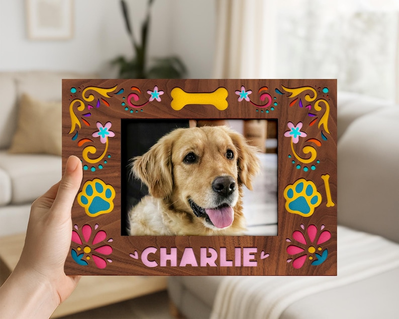 May include: A wooden photo frame with a picture of a golden retriever dog. The frame is brown with colorful floral and paw print designs. The dog's name, "CHARLIE", is printed at the bottom of the frame.