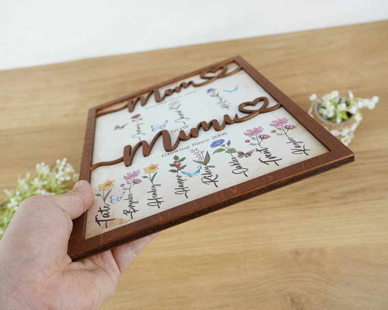 May include: Wooden sign with the words "Mom" and "Mum" in a floral design. The sign features a heart and the text "Growing Since 2000".