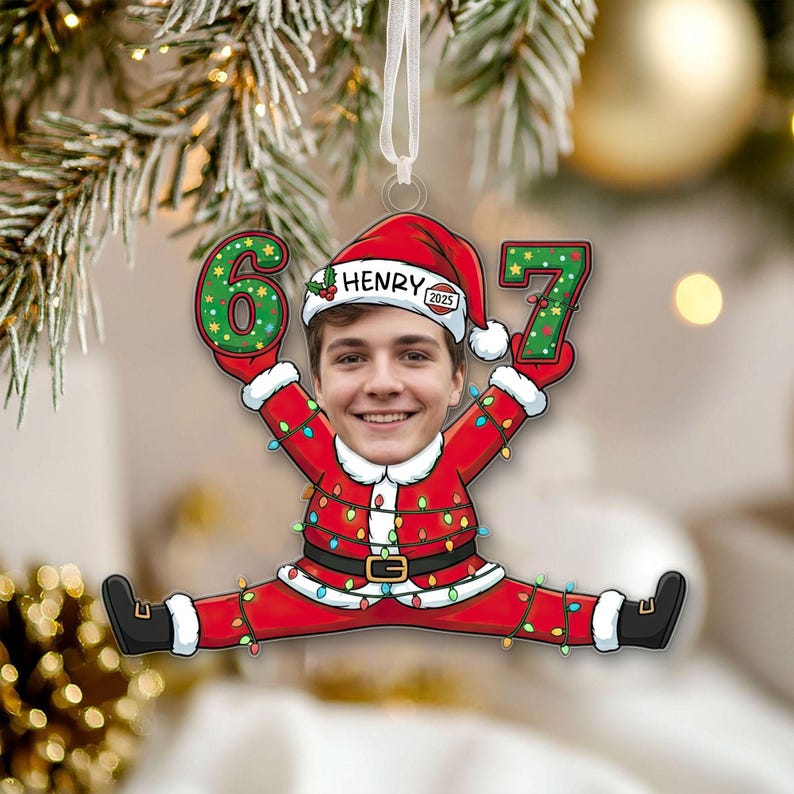 May include: A personalized Christmas ornament featuring a person's face in a Santa Claus suit. The ornament displays the numbers "6" and "7" in green, with the name "HENRY" on the hat. The year "2025" is also visible.