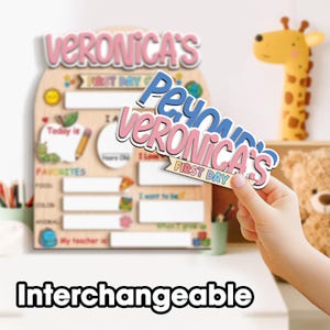 May include: A wooden first day of school sign with the name "Veronica's" in pink and white. The sign includes spaces for "Today is," "Favorites," and "My teacher is." A hand holds a name tag that says "Peyton's Veronica's First Day."