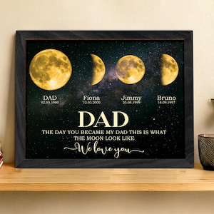 May include: A framed print featuring four phases of the moon against a starry background. The print includes the word "DAD" in large gold letters, along with names and dates. The text reads "The day you became my dad this is what the moon look like. We love you."