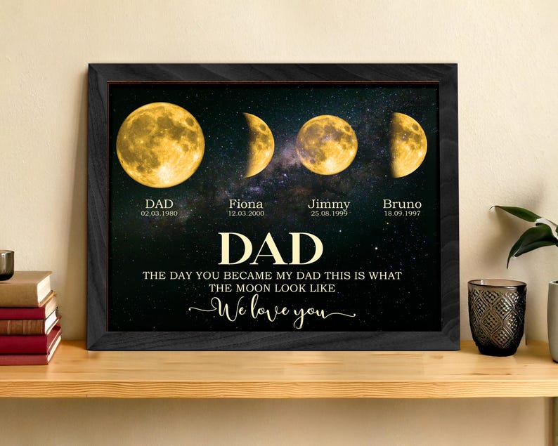 May include: A framed print featuring four phases of the moon against a starry background. The print includes the word "DAD" in large gold letters, along with names and dates. The text reads "The day you became my dad this is what the moon look like. We love you."
