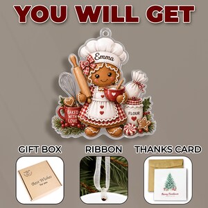 May include: A gingerbread person ornament wearing a chef hat labeled Emma, holding a rolling pin and bowl, surrounded by baking items like a whisk, flour jar, and red mug labeled Baked With Love. Includes a gift box, ribbon, and a Christmas card.