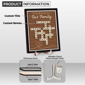 May include: A wooden sign with a brown background and a black frame. The sign features a scrabble tile crossword puzzle with the words "Our Family" at the top. The sign is 8mm thick and has a wooden stand and a metal hanger hook.