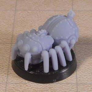 May include: A pair of gray, 3D printed, spider-like creatures with multiple legs. The creatures are connected and have a round, textured body.