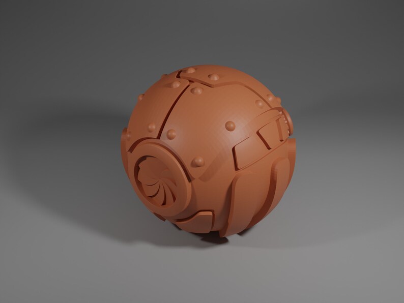 May include: A round, brown, metallic object with a design on the front. The object has a textured surface and appears to be made of metal.