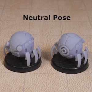 May include: Two gray, spherical robots with multiple legs, each on a black base. The robots are in a neutral pose, with their legs extended. The text "Neutral Pose" is written above the robots.