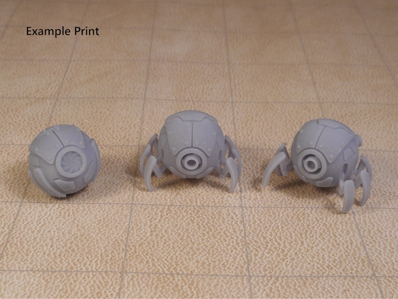 May include: Three 3D printed gray robots with round bodies and six legs each. The robots have a circular design on the front of their bodies.