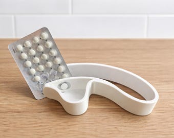 Abre-pastillas con compartimento de recogida, abre-blísteres