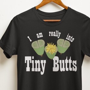 May include: Black t-shirt with a graphic of three green acorns and a yellow flower with the text "I am really into Tiny Butts" printed in white.