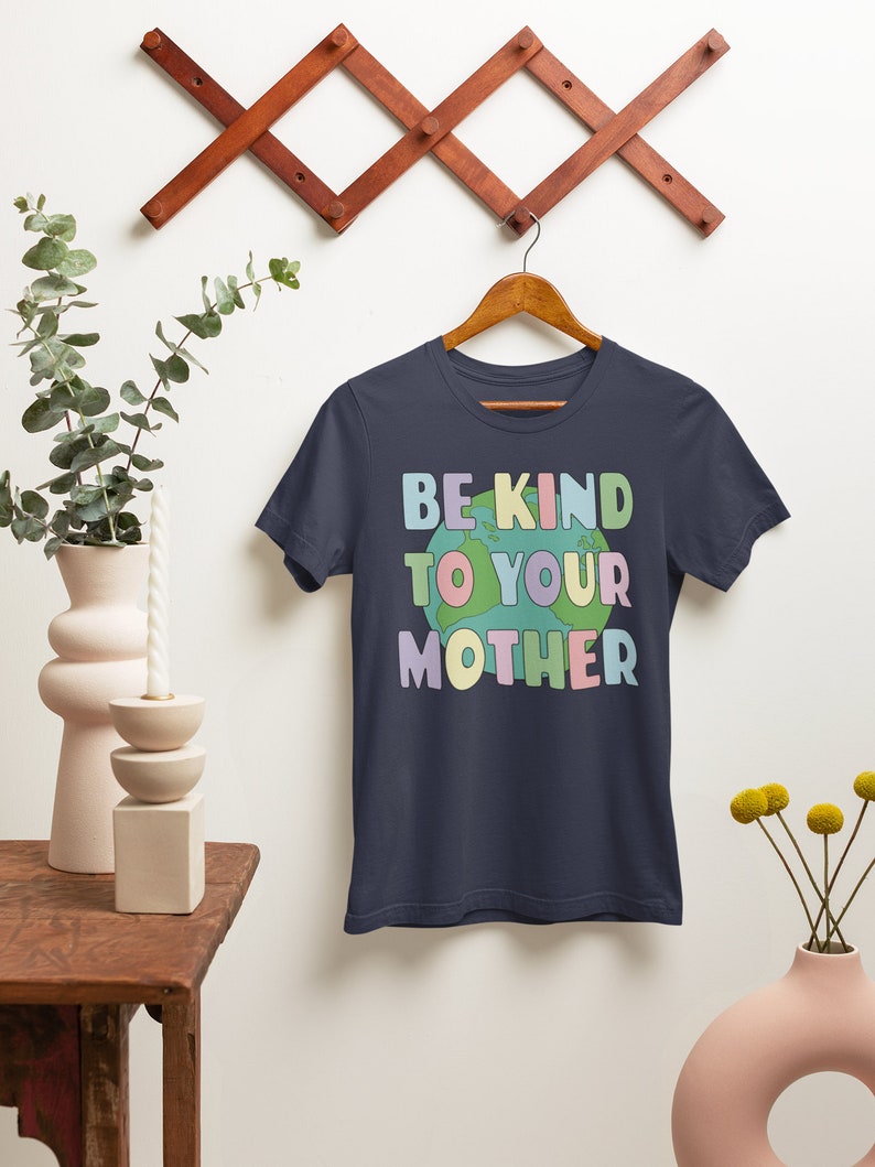 May include: A navy blue t-shirt with the text "Be Kind To Your Mother" in rainbow colors with a cartoon earth graphic.