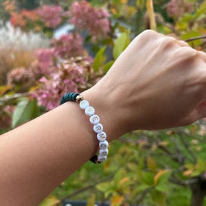 May include: A green beaded bracelet with white beads that spell out the word "evermore".