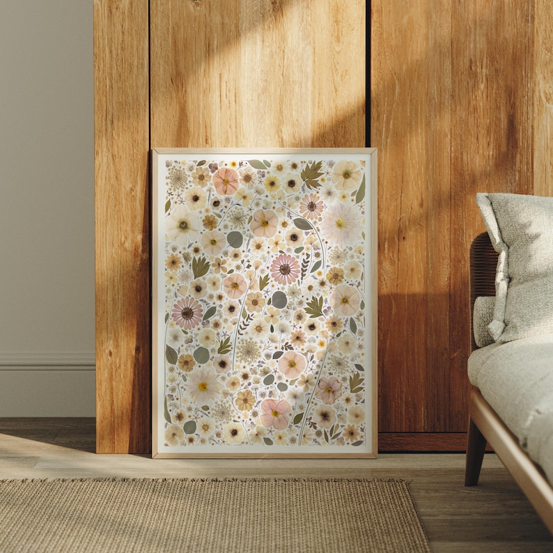 May include: A rectangular wall art print featuring a dense, repeating pattern of pressed-style flowers and leaves in muted shades of cream, beige, soft pink, and sage green, enclosed within a simple, light-toned wooden frame.
