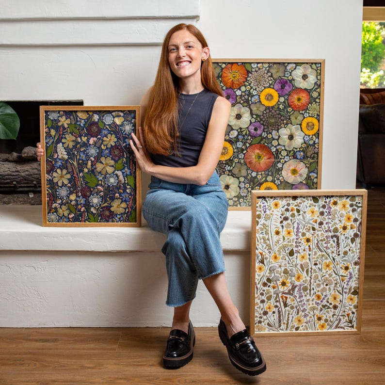 May include: Three rectangular framed art pieces featuring pressed flower arrangements. One frame displays a dark blue background with dense floral patterns, while the other two feature light backgrounds with vibrant yellow, orange, and white flowers.