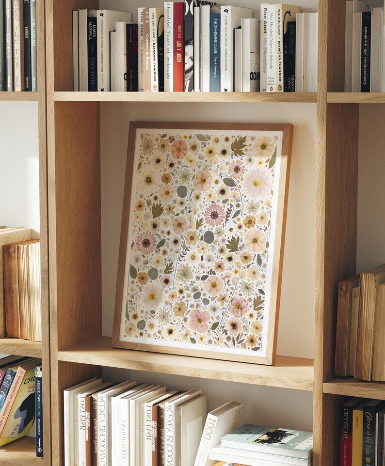 May include: A rectangular framed print featuring a dense, repeating pattern of pressed flowers in shades of soft pink, cream, muted yellow, and sage green. The artwork is encased in a light-toned wooden frame and displays a variety of botanical shapes.
