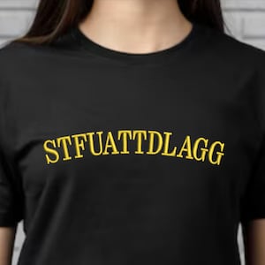 May include: Black t-shirt with the text "STFUATTDLAGG" embroidered in yellow.