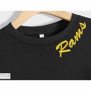 May include: Black sweatshirt with a gold embroidered "Rams" on the front. The sweatshirt has a crew neck and a size tag that says "M".