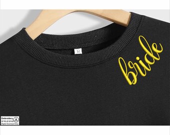 May include: Black sweatshirt with the word "bride" embroidered in yellow on the right shoulder. The sweatshirt has a crew neck and a size tag that says "M".
