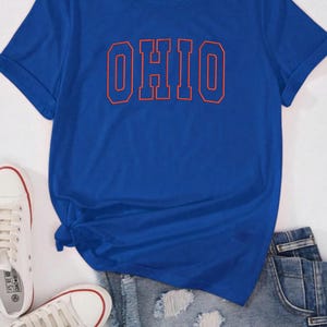 May include: A royal blue t-shirt with a red outline of the word "OHIO" printed on the front.