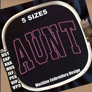 May include: A pink embroidered design of the word "AUNT" in a bold, blocky font. The design is displayed on a black embroidery hoop with the text "5 SIZES" and "Machine Embroidery Design" visible.