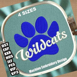 May include: Machine embroidery design featuring a blue paw print with the word "Wildcats" in white cursive lettering. The design is on a light blue fabric and includes the text "4 SIZES" and "Machine Embroidery Design".