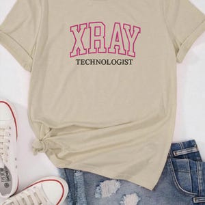 K&ouml;nnte beinhalten: Ein beiges T-Shirt mit einem rosa Umriss des Wortes "XRAY" und dem Text "TECHNOLOGIST" darunter.